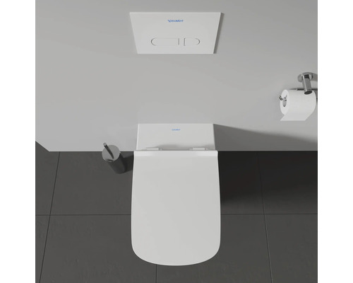Vue de dessus de toilettes avec plaque de commande et brosse de toilette