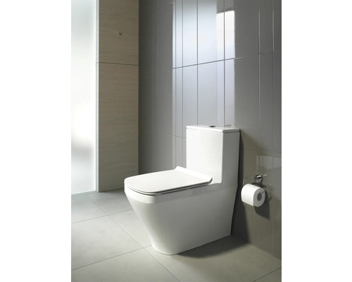 Toilettes blanches dans une salle de bains avec des carreaux gris.