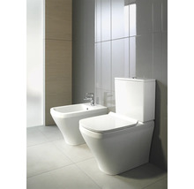 Bidet et WC sur pied dans salle de bains avec carrelage gris.