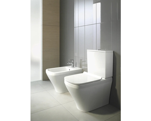 Bidet et WC sur pied dans salle de bains avec carrelage gris.