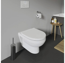 WC suspendu dans une salle de bains avec brosse de toilette, porte-papier toilette et petite table