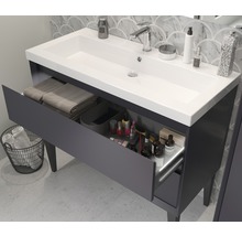 Meuble sous-lavabo avec tiroir ouvert, serviettes et produits cosmétiques dans la salle de bain