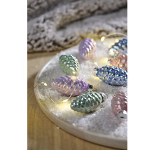 Dekorative Zapfen mit Lichterkette auf einem Teller mit Kunstschnee