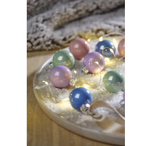 Verschiedenfarbige Weihnachtskugeln mit Lichterkette auf einem Teller