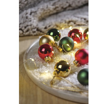 Dekorative Weihnachtskugeln auf einem Teller mit Kunstschnee und Lichterkette