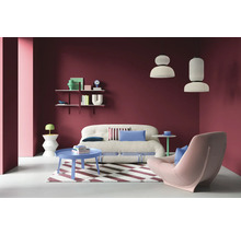 Wohnzimmer mit Sofa, Sessel, Couchtisch und Regalen an einer farbigen Wand