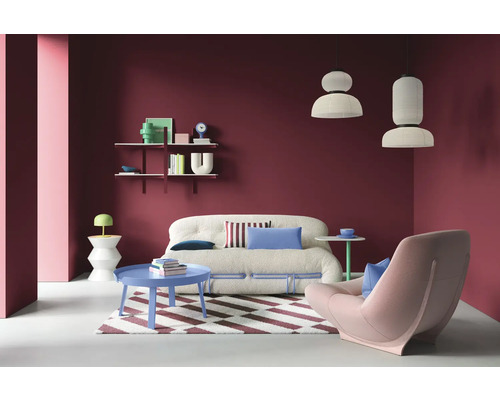 Salon avec canapé, fauteuil, table basse et étagères sur un mur coloré