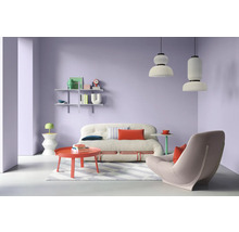 Wohnzimmer mit Sofa, Sessel, Tisch und Regalen vor lila Wand