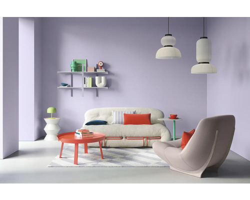 Salon avec canapé, fauteuil, table et étagères devant un mur violet