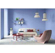 Salon avec canapé, fauteuil, table basse, étagères et suspensions dans une pièce lumineuse