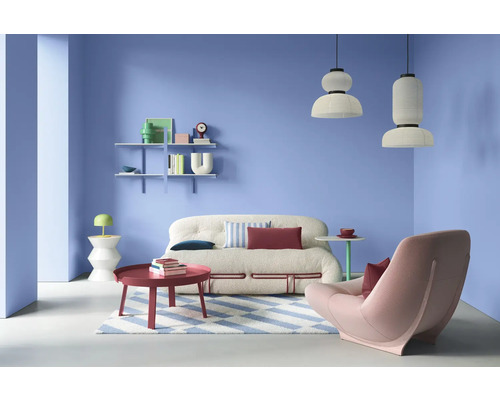 Salon avec canapé, fauteuil, table basse, étagères et suspensions dans une pièce lumineuse