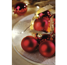 Boules de Noël rouges avec ruban sur une assiette avec guirlande lumineuse
