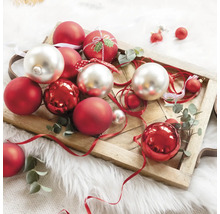 Boules de Noël décoratives rouges et argentées sur un plateau en bois.