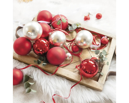 Boules de Noël décoratives rouges et argentées sur un plateau en bois.