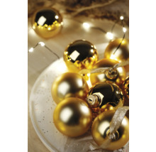 Dekorative goldene Weihnachtskugeln auf einem Teller mit Lichterkette
