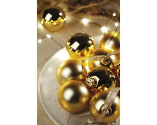 Dekorative goldene Weihnachtskugeln auf einem Teller mit Lichterkette