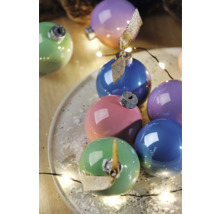 Boules de Noël multicolores sur une assiette, décorées d'une guirlande lumineuse