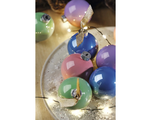 Boules de Noël multicolores sur une assiette, décorées d'une guirlande lumineuse