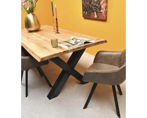 Coin repas moderne avec une table en bois massif, un piètement en X en métal noir et deux chaises rembourrées grises avec accoudoirs.
