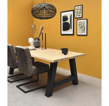 Salle à manger avec table en bois massif, pieds en métal noir, chaises rembourrées grises et suspension cage noire devant un mur jaune.