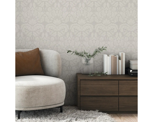 Vue d'une pièce avec papier peint à motifs floraux, fauteuil et commode