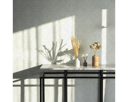 Arrangement décoratif avec des fleurs séchées sur une console devant un mur à motifs.