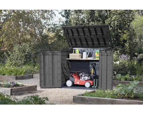 Gartenschrank mit offenem Deckel und Tür im Garten, mit Rasenmäher und Gartengeräten