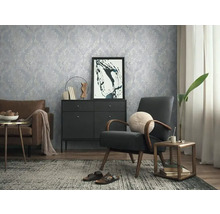 Wohnzimmer mit gemusterter Tapete, Sessel und Kommode