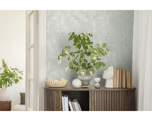 Dekoratives Interieur mit gemusterter Tapete, Kommode, Pflanzen und dekorativen Elementen.
