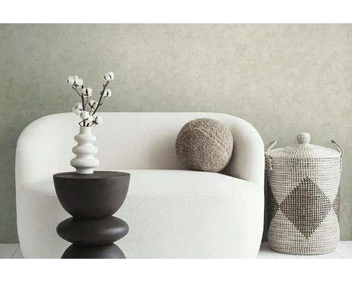 Dekoratives Wohnambiente mit Sofa, Beistelltisch, Vase mit Baumwollzweigen, Kissen und Aufbewahrungskorb