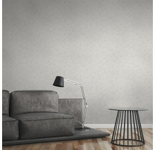 Salon avec canapé gris, lampadaire et table devant un papier peint à motifs