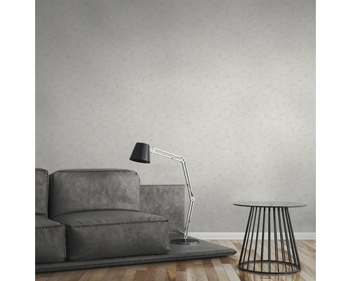 Wohnzimmer mit grauer Couch, Stehlampe und Tisch vor einer gemusterten Tapete