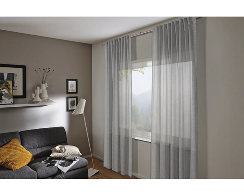 Salon avec rideaux, canapé et lampadaire pour une ambiance chaleureuse