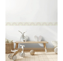 Kinderzimmer mit Holzbank, Laufrad, Spielzeug und Wandbordüre mit Regenbogenmuster