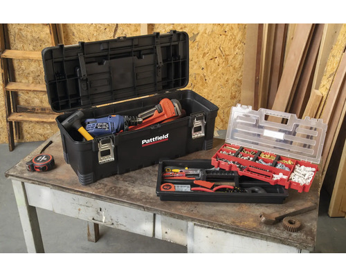 Boîte à outils ouverte avec des outils et un assortiment de petites pièces sur une table.