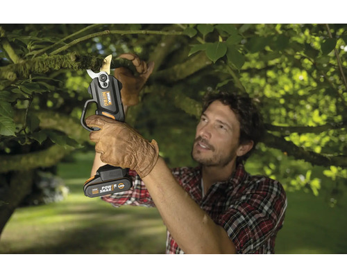 Un homme coupe une branche avec un sécateur à batterie Worx Nitro.