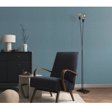 Salon avec fauteuil, lampadaire et commode devant un mur bleu