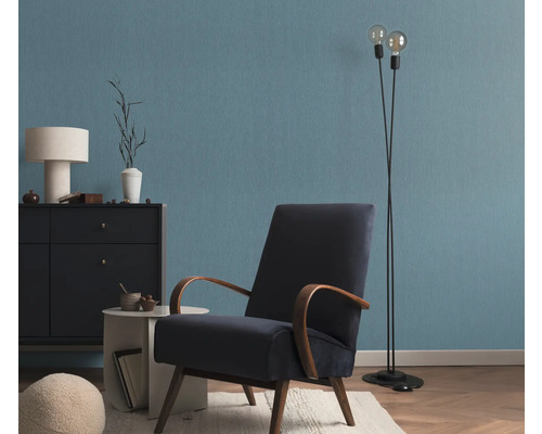 Salon avec fauteuil, lampadaire et commode devant un mur bleu