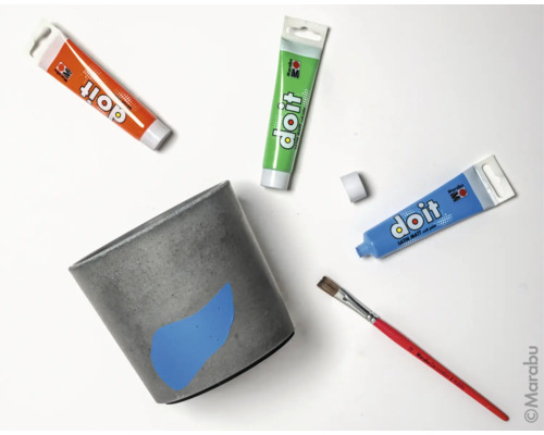 Pot de fleurs en béton avec tubes de peinture et pinceau