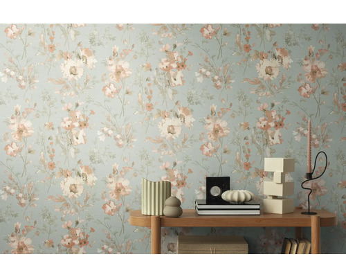 Gros plan d'un mur avec du papier peint à fleurs et une table d'appoint avec des objets de décoration.