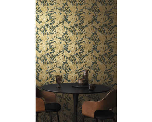 Une pièce avec un papier peint à motif de feuilles, une table à manger et des chaises.