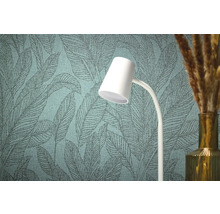 Gros plan d'un papier peint structuré avec un motif de feuilles, une lampe blanche et un vase avec de l'herbe décorative