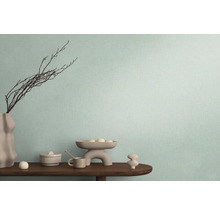 Dekoratives Arrangement auf einem Holztisch vor einer Wand mit Textiltapete