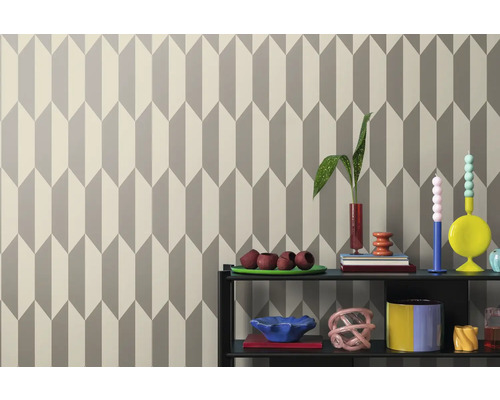 Papier peint à motif de flèches géométriques derrière une étagère avec des objets de décoration.