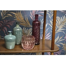 Vases décoratives et objets en verre sur une étagère en bois devant un papier peint à motifs