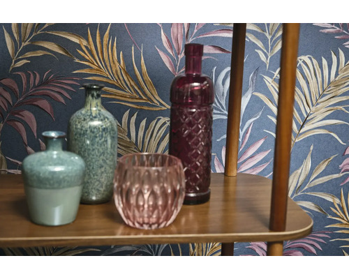 Vases décoratives et objets en verre sur une étagère en bois devant un papier peint à motifs