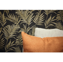 Gros plan d'un mur avec papier peint à motifs de feuilles et coussins décoratifs