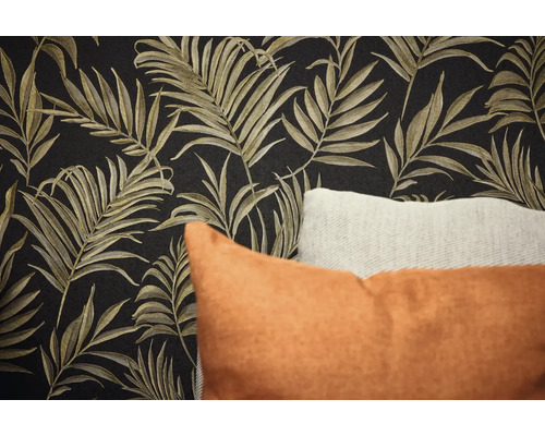 Gros plan d'un mur avec papier peint à motifs de feuilles et coussins décoratifs