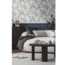 Salon avec papier peint floral, canapé, table basse et accessoires décoratifs pour une ambiance chaleureuse.