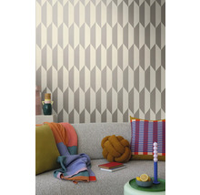 Salon avec papier peint géométrique gris et blanc derrière un canapé gris